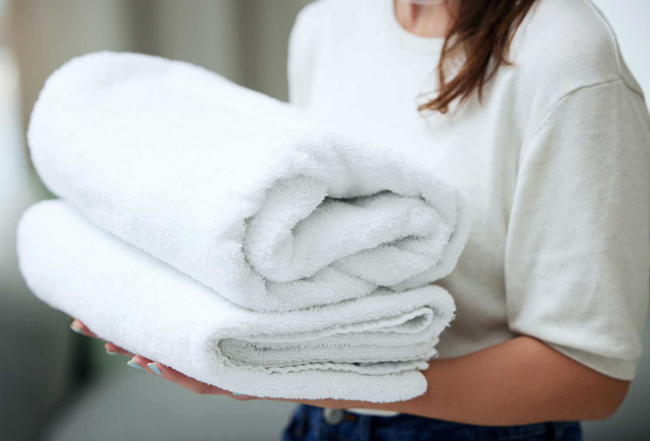 Shot of an unrecognizable woman folding towels at home